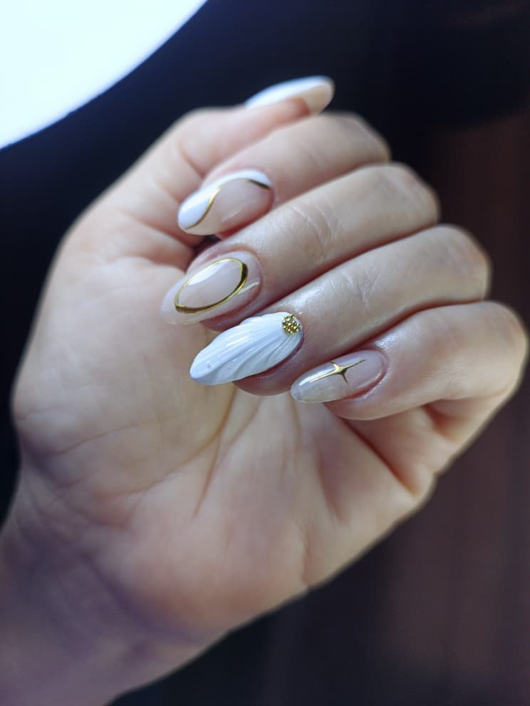 Manicura blanca con diseño floral en dorado